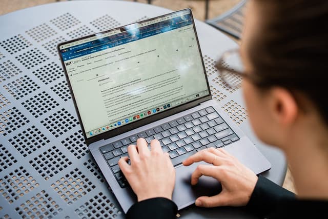 A person sitting at a table with their laptop looking at the MIT Learn platform.