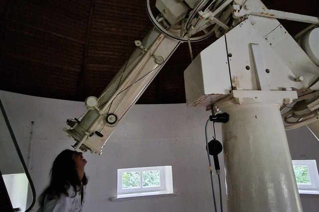 Shreya Mogulothu squints up into the eyepiece of large telescope under a dome