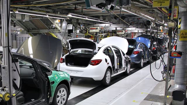 A row of cars on the assembly line, showcasing the manufacturing process in an automotive factory setting.