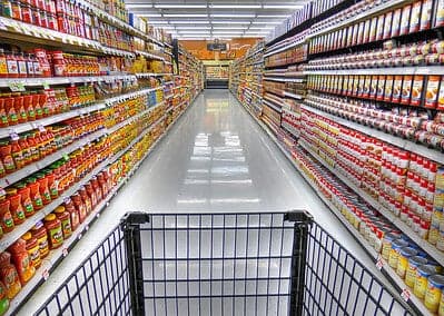 A photo taken at the end of of grocery store aisles, showing countless products displayed on the shelves. 