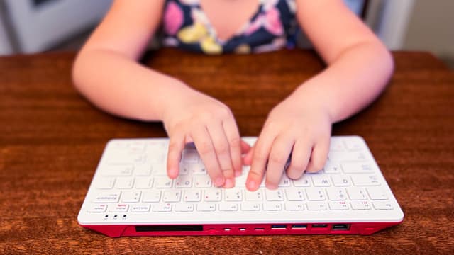 A young student types on a raspberry pi RP400 keyboard.