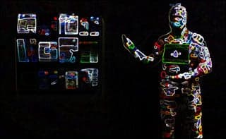 A human form stands in darkness, wearing a bodysuit illuminated from head to toe with various multi-colored circuits.