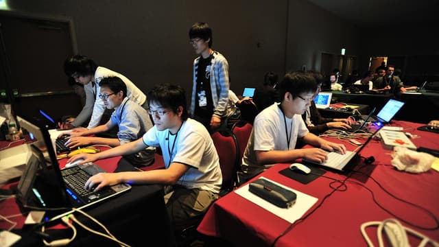 A team of people seated at tables, working on laptop computers.