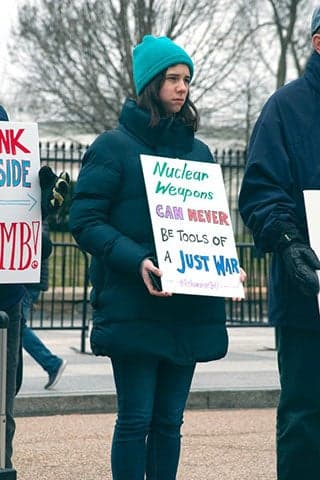 Photo of woman holding a sign protesting nuclear weapons.