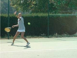 An MIT tennis team member hits a forehand.