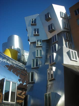 A building made of silver stainless steel, with walls that slope in angles and curves.