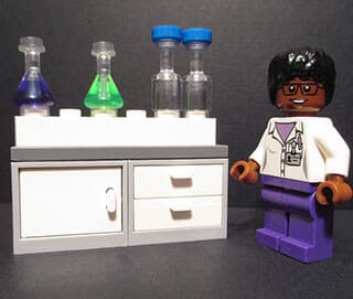 Chemistry equipment and a female African-American scientist are depicted in a Lego® set.